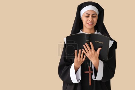 Photo for Young nun reading Bible on beige background - Royalty Free Image