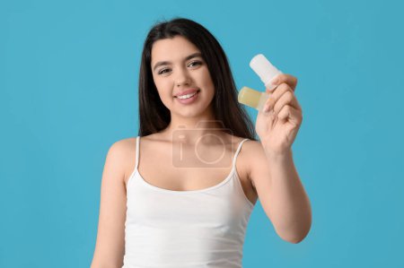 Happy smiling young woman with crystal deodorants on blue background