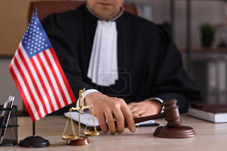 Photo for Mature judge with gavel on table in office, closeup - Royalty Free Image
