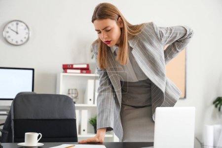 Young businesswoman suffering from back pain in office