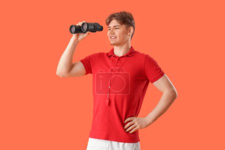 Photo for Male lifeguard with binoculars on orange background - Royalty Free Image
