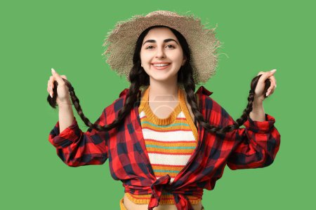 Schöne junge glückliche Frau mit Strohhut auf grünem Hintergrund. Fest Junina (Juni-Fest)