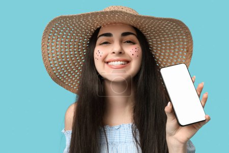 Jeune femme heureuse avec téléphone portable sur fond bleu. Fête Junina (Festival de juin)