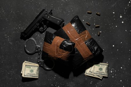 Drogenpakete mit Waffe, Geld und Handschellen vor dunklem Hintergrund