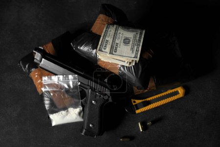 Drogenpakete mit Waffe, Geld und Gebrauchsmesser auf dunklem Hintergrund