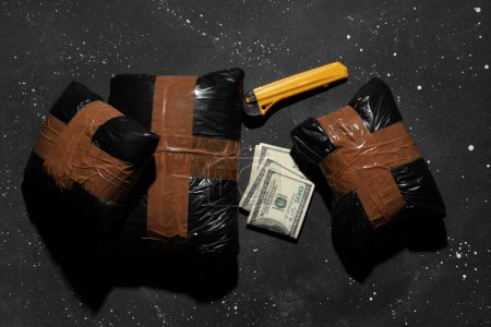 Drogenpakete mit Geld und Gebrauchsmesser auf dunklem Hintergrund