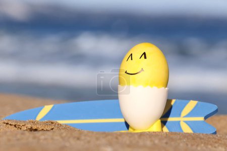 Peintre Oeuf de Pâques et planche de surf sur la plage de la mer