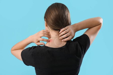 Young woman with mosquito repellent spray on blue background, back view