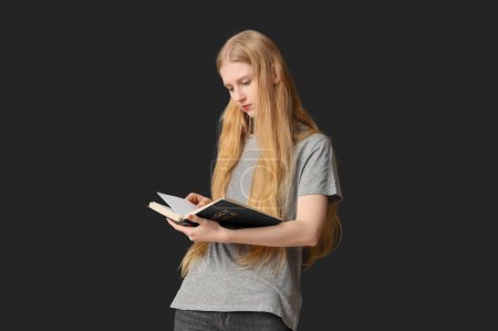 Foto de Hermosa joven leyendo la Biblia sobre fondo negro - Imagen libre de derechos