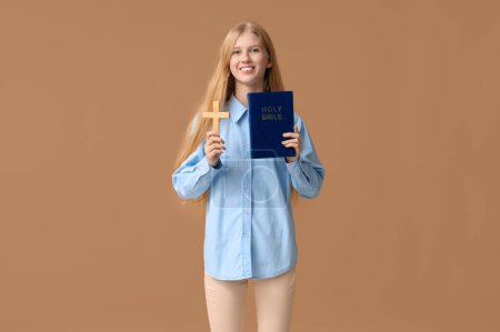 Foto de Hermosa joven feliz mujer con cruz de madera y la Biblia sobre fondo marrón - Imagen libre de derechos