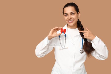 Retrato de una doctora apuntando al modelo tiroideo sobre fondo beige