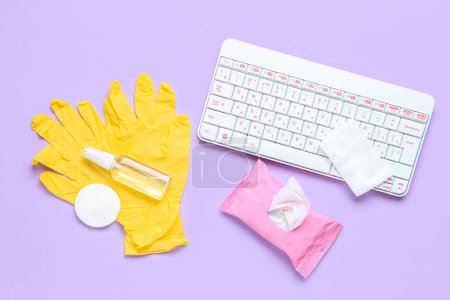Gummihandschuhe mit Flasche Desinfektionsmittel, Feuchttücherpackung und Tastatur auf lila Hintergrund