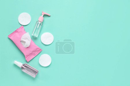 Photo for Bottles of sanitizer with wet tissues pack and cotton pads on turquoise background - Royalty Free Image
