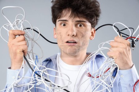 Electrocuted young man with burnt face and cables on light background, closeup