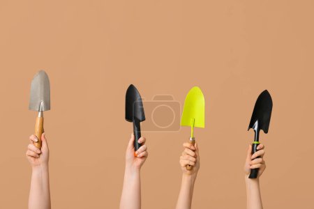 Téléchargez les photos : Mains féminines avec différentes pelles de jardinage sur fond de couleur - en image libre de droit