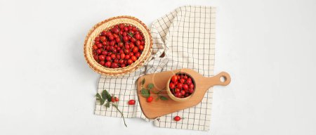 Photo for Bowl and wicker basket with fresh rose hip berries on white background - Royalty Free Image