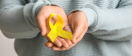 Photo for Woman holding yellow ribbon, closeup. Banner for Sarcoma Cancer Awareness Month - Royalty Free Image
