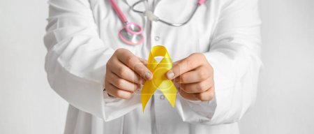 Photo for Doctor holding yellow ribbon on light background, closeup. Banner for Sarcoma Cancer Awareness Month - Royalty Free Image