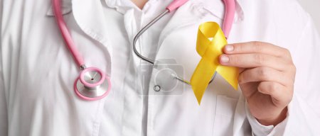 Photo for Doctor holding yellow ribbon, closeup. Banner for Sarcoma Cancer Awareness Month - Royalty Free Image