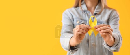 Photo for Woman holding yellow ribbon on color background with space for text. Banner for Sarcoma Cancer Awareness Month - Royalty Free Image