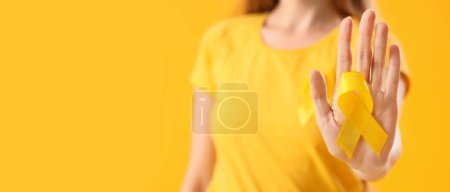 Photo for Woman holding yellow ribbon on color background with space for text, closeup. Banner for Sarcoma Cancer Awareness Month - Royalty Free Image