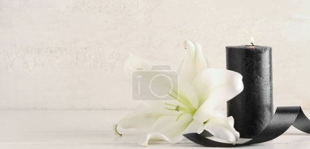 Burning candle, lily flower and black funeral ribbon on white background with space for text