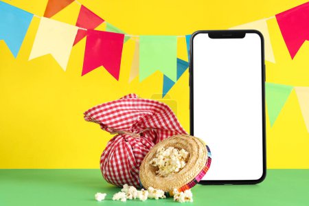 Téléphone portable avec écran blanc, paquet, sombrero et pop-corn sur fond de couleur