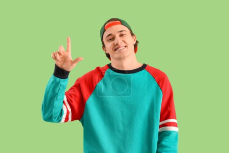 Photo for Young man showing loser gesture on green background - Royalty Free Image