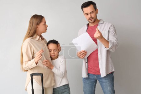 Sad little girl and her parents getting divorce on light background. Divorce concept