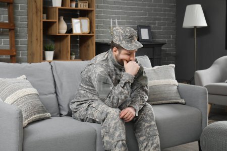 Thoughtful Jewish soldier sitting on sofa at home