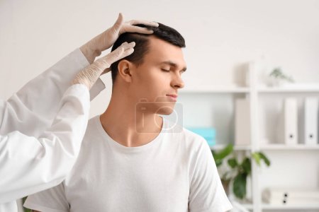 Photo for Trichologist examining young man's hair in clinic, closeup - Royalty Free Image