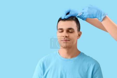 Photo for Young man with marks receiving injection for hair growth on blue background, closeup - Royalty Free Image