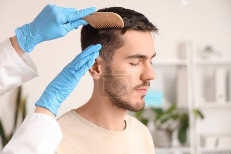 Photo for Doctor combing young man's hair in clinic, closeup - Royalty Free Image