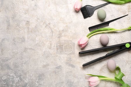 Photo for Flattening iron with hairdressing brushes, tulips and Easter eggs on light grunge background - Royalty Free Image