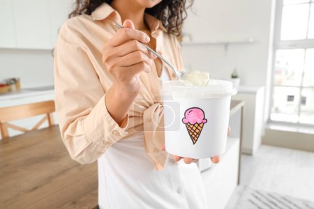Téléchargez les photos : Jeune femme afro-américaine avec panier de crème glacée en cuisine - en image libre de droit