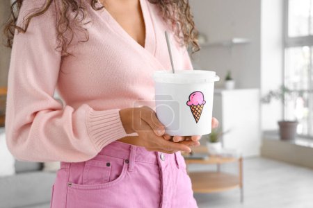 Téléchargez les photos : Jeune femme afro-américaine avec panier de crème glacée à la maison - en image libre de droit