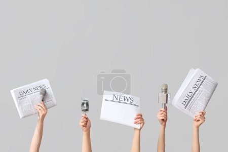 Téléchargez les photos : Mains féminines avec journaux et microphones sur fond gris - en image libre de droit