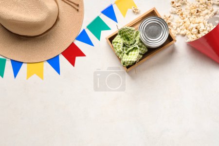 Composition with popcorn, canned corn, hat and flags for Festa Junina celebration on light background