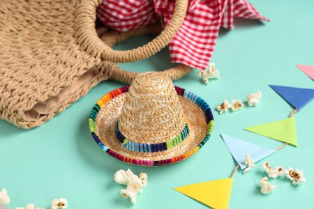 Mini sombrero, wicker bag, popcorn and flags for Festa Junina celebration on color background