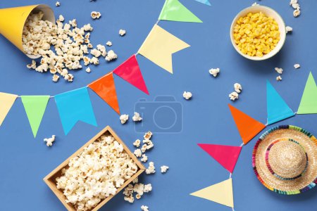 Composition with tasty popcorn, corn and decor for Festa Junina celebration on blue background