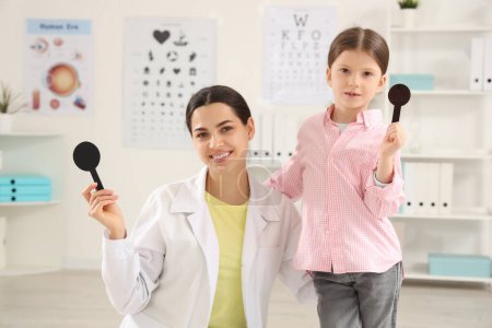 Female ophthalmologist and little girl with occluders in clinic