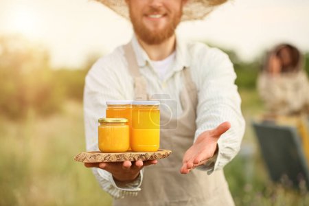 Beekeeper with honey in jars at apiary
