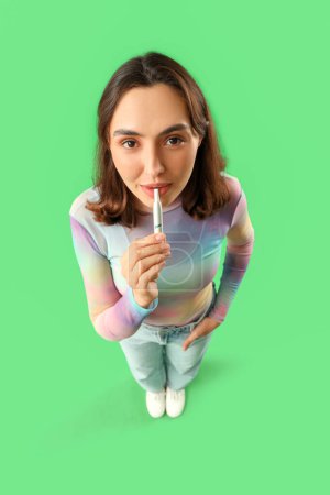 Téléchargez les photos : Jeune femme fumant cigare électronique sur fond vert - en image libre de droit