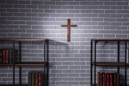 Foto de Cruz de madera colgando en la pared de ladrillo gris en la habitación - Imagen libre de derechos