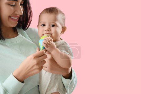 Jeune femme donnant son petit bébé grignoteuse avec de la nourriture sur fond rose, gros plan