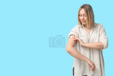 Femme avec capteur de glucose pour mesurer le taux de sucre dans le sang sur fond bleu. Concept de diabète