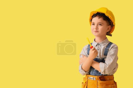 Téléchargez les photos : Mignon petit constructeur avec tournevis jouet sur fond jaune - en image libre de droit