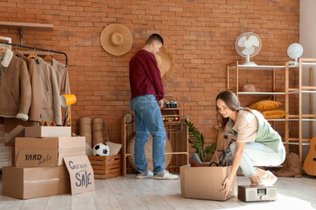 Photo for Young couple packing in room of unwanted stuff - Royalty Free Image