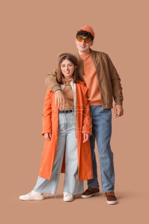 Photo for Young beautiful couple in stylish coats on beige background - Royalty Free Image