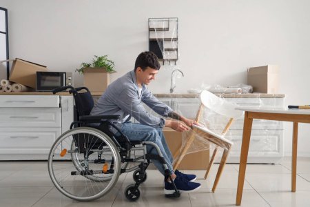 Téléchargez les photos : Jeune homme en fauteuil roulant enveloppant pendant la réparation à la maison - en image libre de droit